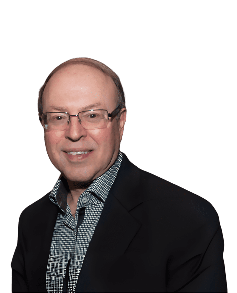 A smiling man in glasses wearing a dark blazer and checkered shirt.