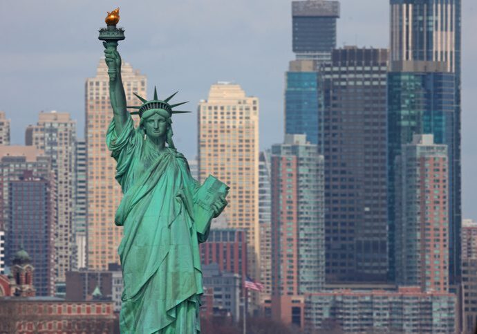 Statue of Liberty standing tall with city skyline in the background.